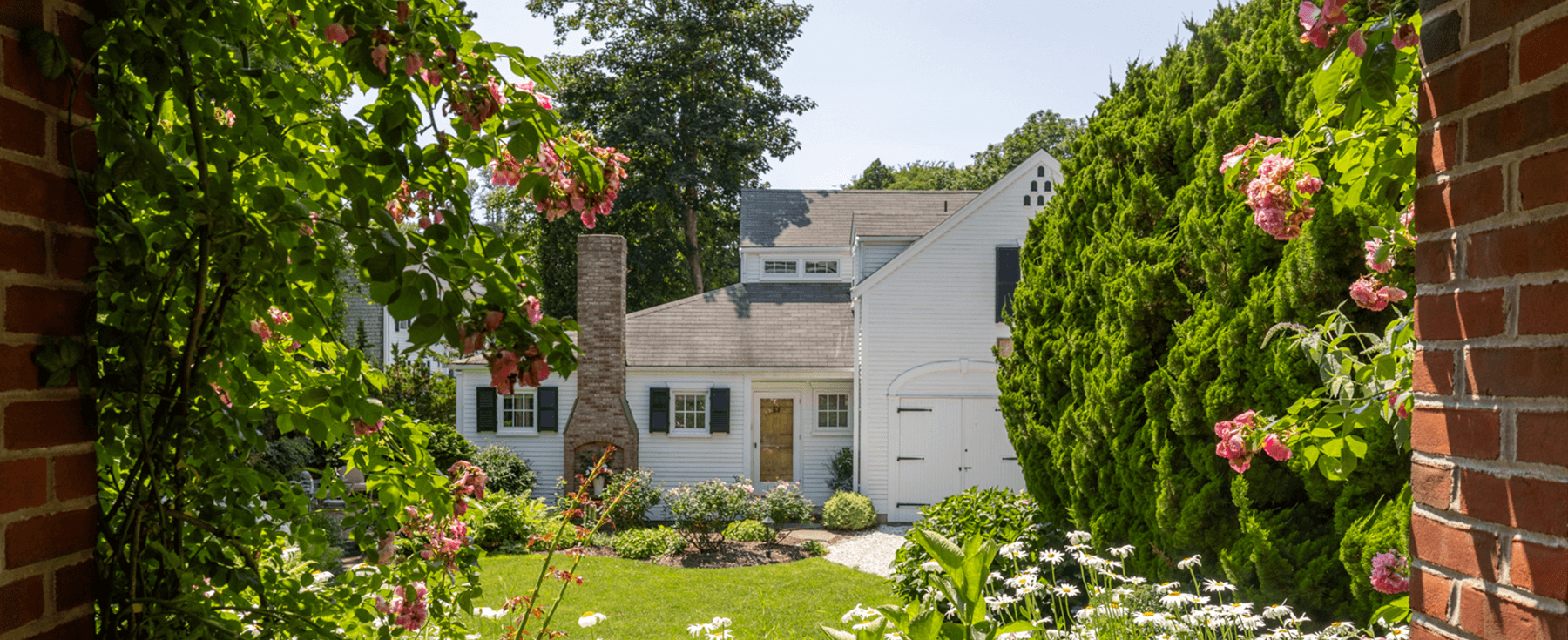 White home viewed through a garden with flowers and exterior windows